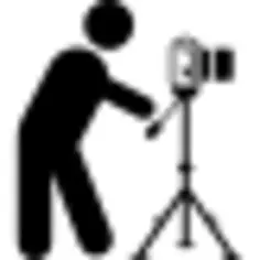 Photographer standing behind photo camera on a tripod from side view